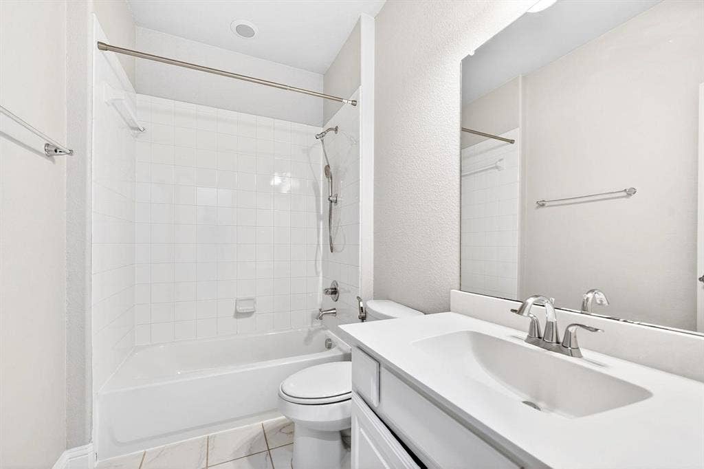Full bathroom featuring a white tub-shower combination with subway tile surround, a built-in vanity with white countertop and integrated sink, chrome fixtures, and a large wall-mounted mirror