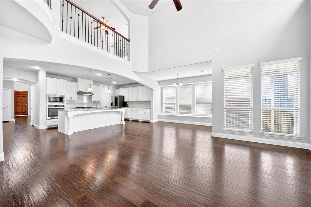 Open-concept living space featuring high ceilings, wood-finish flooring, and multiple large windows