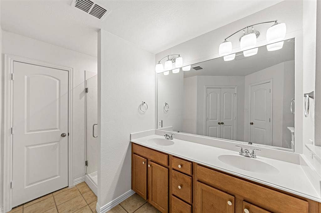7916 Hannah Street, Plano, TX 75025 Double vanity with wood cabinetry, dual undermount sinks, and a large mirror with integrated lighting
