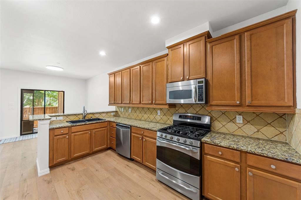7916 Hannah Street, Plano, TX 75025 Kitchen featuring wood-finish cabinetry, granite countertops, and stainless steel appliances
