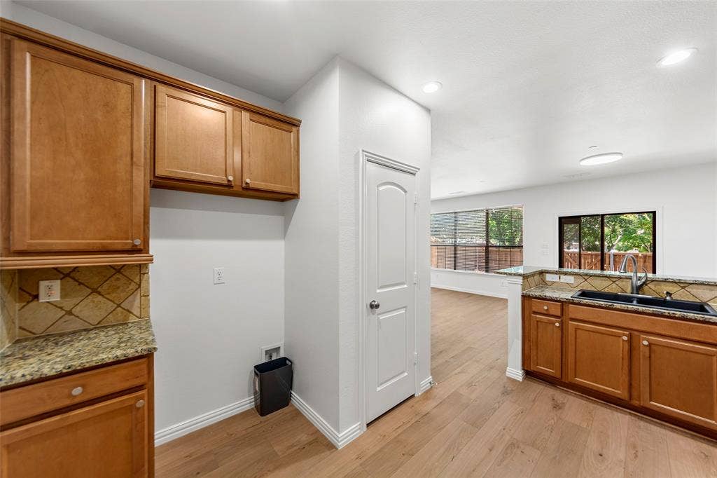 7916 Hannah Street, Plano, TX 75025 Open-concept living space featuring wood-finish flooring, recessed lighting, and a kitchen with wood cabinetry, stone countertops, and a tile backsplash