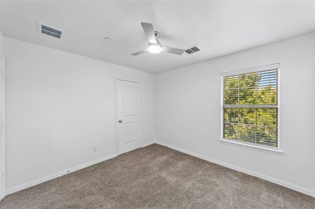 7916 Hannah Street, Plano, TX 75025 Carpeted interior room featuring a modern ceiling fan, large window with blinds, white trim, and a white interior door