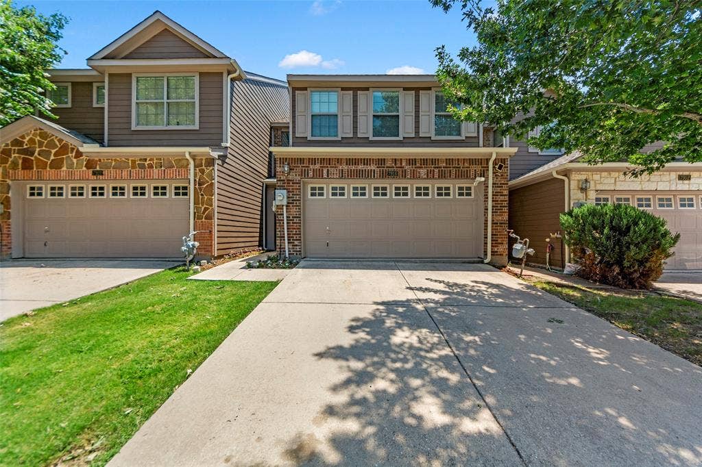 7916 Hannah Street, Plano, TX 75025 Two-story residence featuring a two-car garage with paneled doors, brick veneer, and stone accents