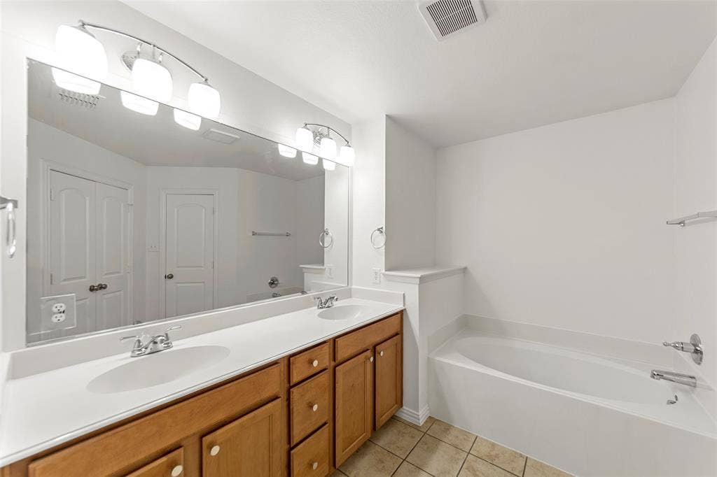 7916 Hannah Street, Plano, TX 75025 Bathroom featuring a double vanity with white countertops and wood cabinetry