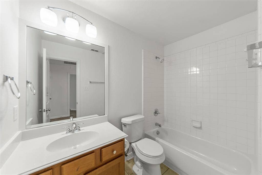 7916 Hannah Street, Plano, TX 75025 Bathroom featuring a wood-finish vanity with an integrated sink, a large wall-mounted mirror, and a three-light fixture