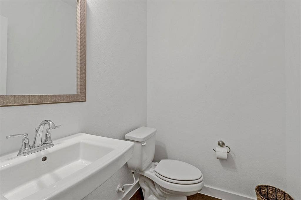 616 Collier Drive, Plano, TX 75075 Powder room featuring a pedestal sink, chrome faucet, framed mirror, and white toilet