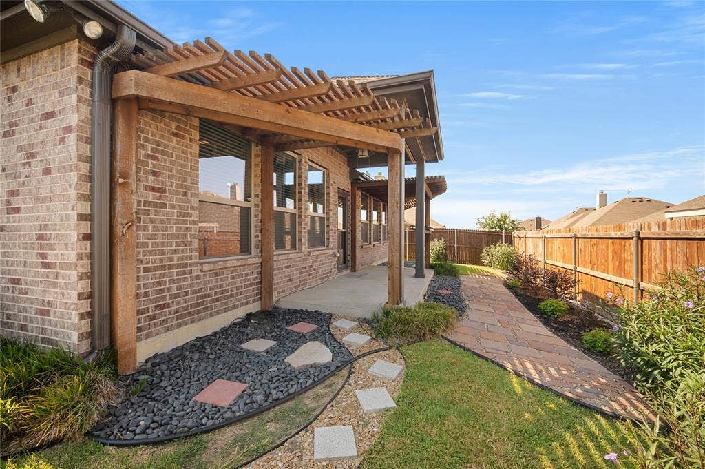 231 Carson Drive, Waxahachie, TX 75167 Double pergolas with a fan and bar seating under the patio. Tons of landscaping lining the fence on all sides.