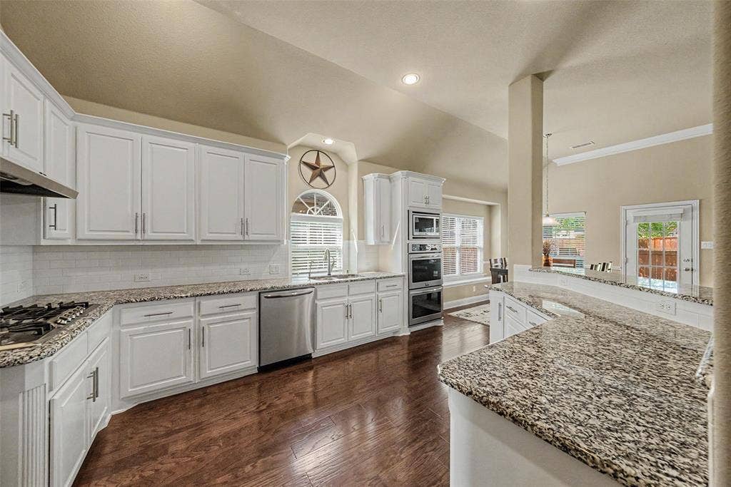 Kitchen featuring white cabinetry, granite countertops, stainless steel appliances, a gas cooktop, and wood-finish flooring