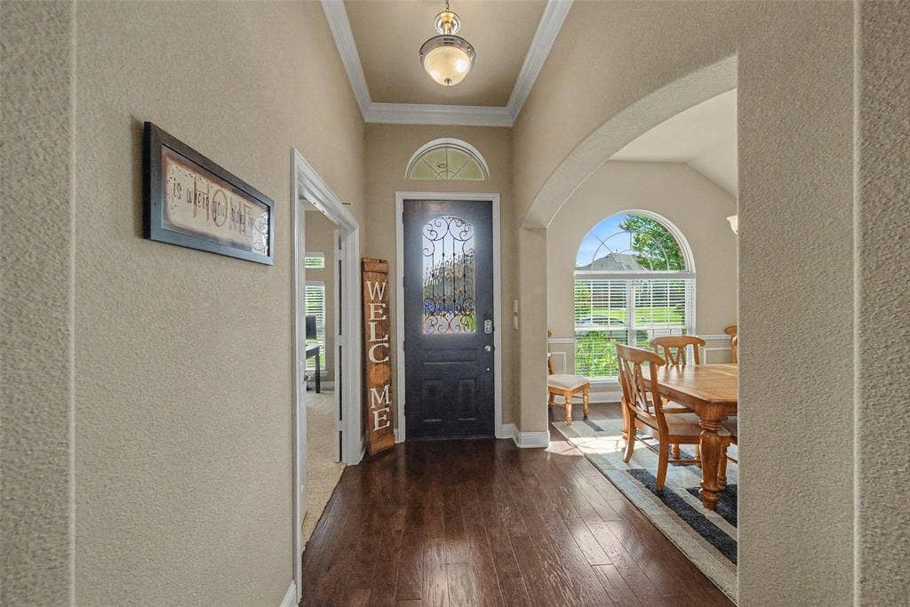 Entryway featuring rich wood-finish flooring, an arched doorway, and a decorative glass-paneled entry door with an arched transom