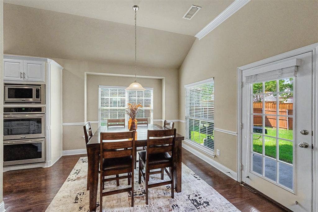 Dining area featuring wood-finish flooring, vaulted ceiling, and crown molding