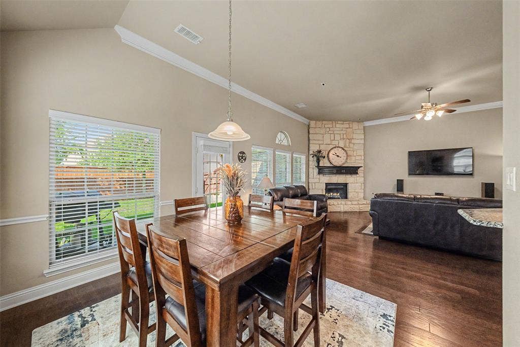 Open-concept living space featuring wood-finish flooring, a vaulted ceiling, and a stone-clad fireplace