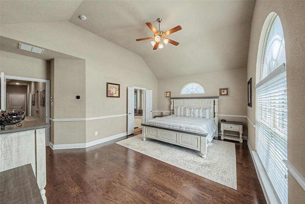 Spacious room featuring vaulted ceilings, wood-finish flooring, and crown molding