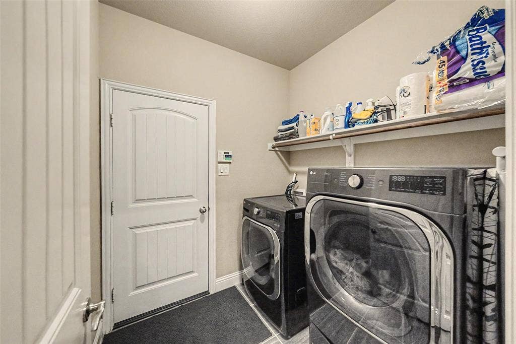 Dedicated laundry area featuring a white paneled door, light neutral wall paint, and a built-in wall shelf