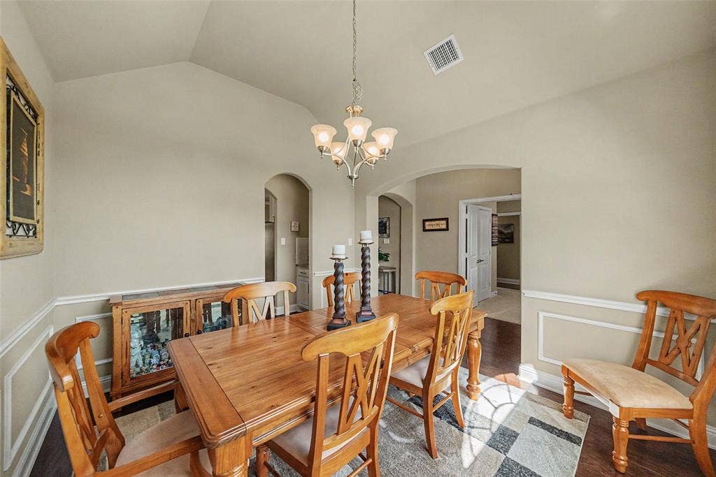Vaulted ceiling with an elegant chandelier, framed by arched doorways, and featuring wainscoting and crown molding details
