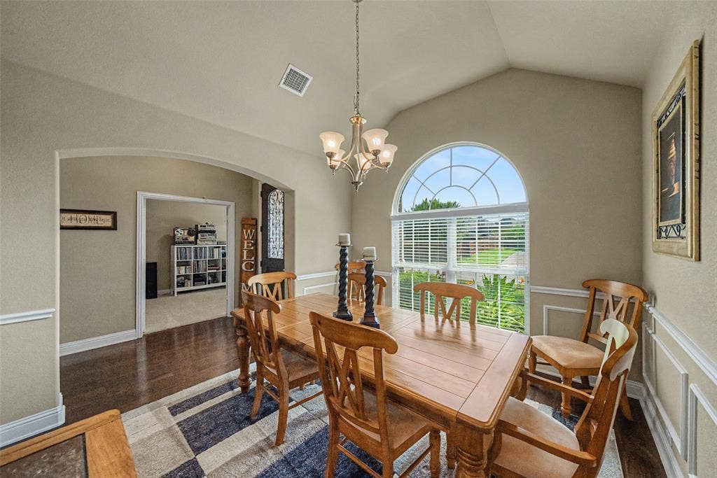 Dining space featuring a vaulted ceiling and an arched window with horizontal blinds