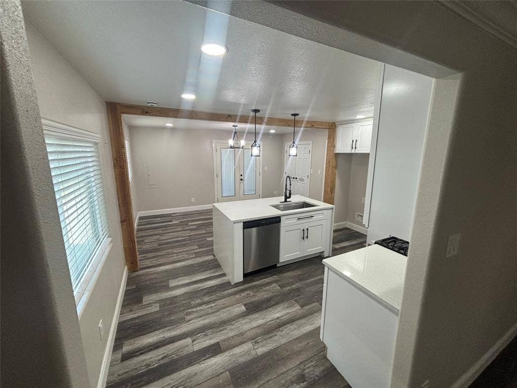 910 NE 31st, Grand Prairie, TX 75050 Open-concept kitchen featuring a central island with an undermount sink, stainless steel dishwasher, and white shaker cabinetry