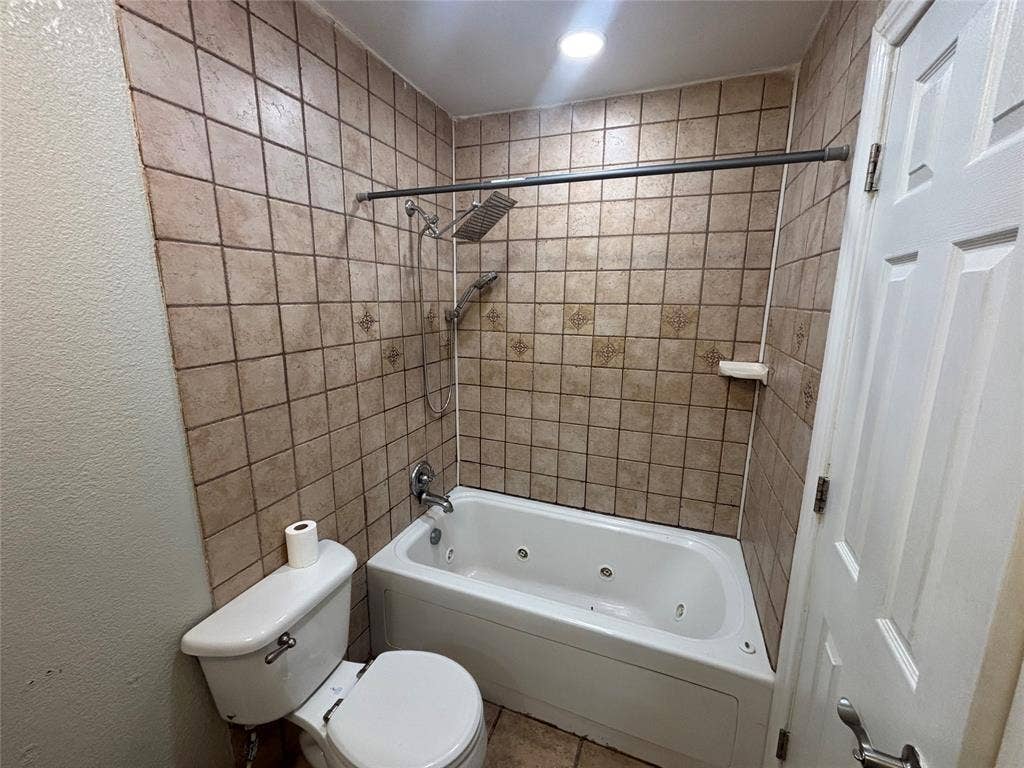 910 NE 31st, Grand Prairie, TX 75050 Bathroom featuring a built-in jetted tub and shower combination with a rainfall showerhead