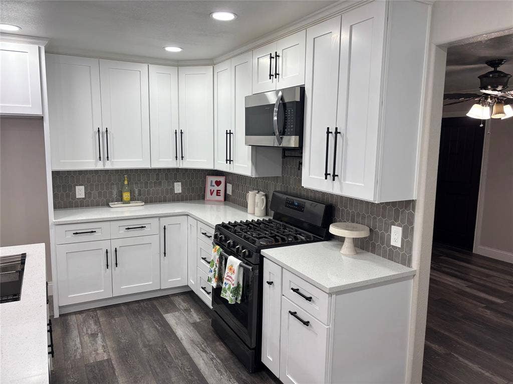 910 NE 31st, Grand Prairie, TX 75050 Kitchen featuring white shaker-style cabinetry with matte black hardware, white countertops, and a gray picket tile backsplash