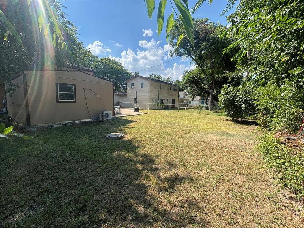 910 NE 31st, Grand Prairie, TX 75050 Spacious backyard with a detached shed featuring a window and two exterior units