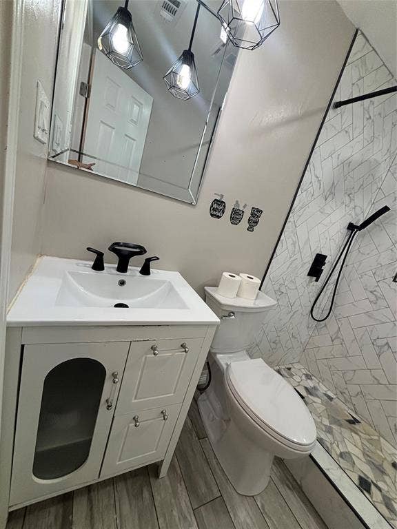 910 NE 31st, Grand Prairie, TX 75050 Bathroom featuring a single vanity with storage, tile flooring, and a walk-in shower with herringbone-patterned tile and a built-in bench