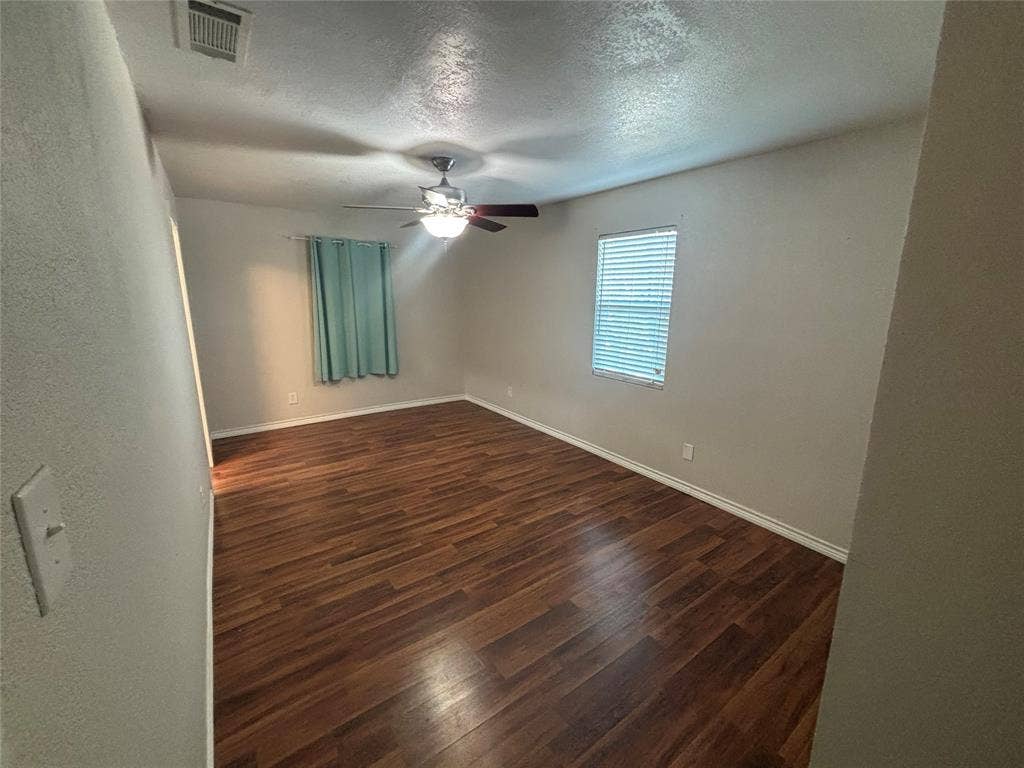 910 NE 31st, Grand Prairie, TX 75050 Spacious room featuring wood-finish flooring, light-colored walls, and a ceiling fan with integrated lighting