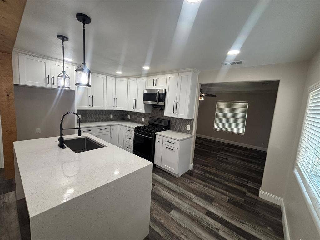 910 NE 31st, Grand Prairie, TX 75050 Modern kitchen featuring white shaker cabinetry, an integrated island with a waterfall countertop, and a black gooseneck faucet