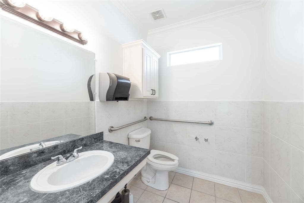2840 Keller Springs Road, #1201, Carrollton, TX 75006 Vanity with an oval sink and a dark countertop, white wall-mounted cabinetry, white tiled walls, and a small rectangular window