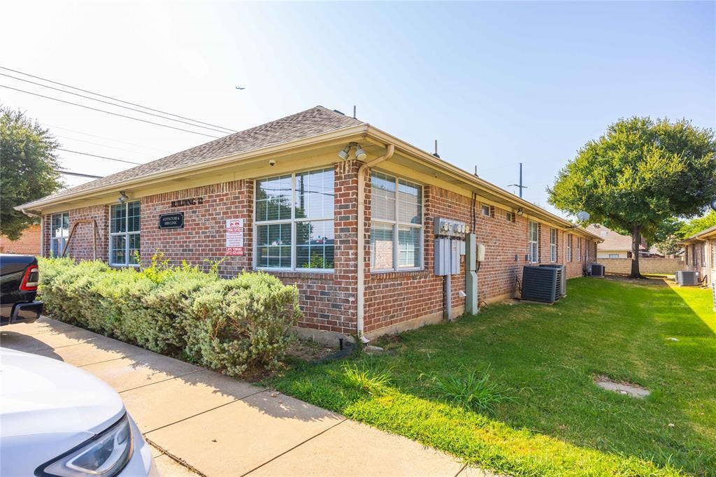 2840 Keller Springs Road, #1201, Carrollton, TX 75006 Brick exterior with multiple windows, a sidewalk, and a landscaped shrub border