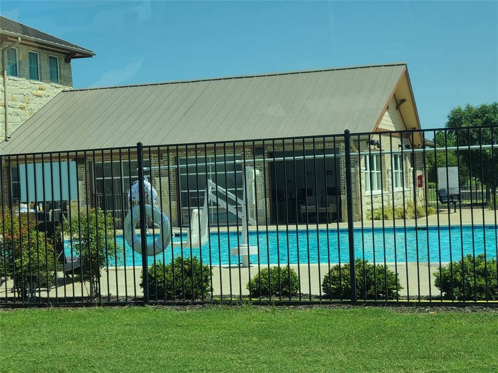 2810 Green Circle Drive, Mansfield, TX 76063 Fenced swimming pool with a stone and brick pool house featuring a metal roof and large glass paneled doors