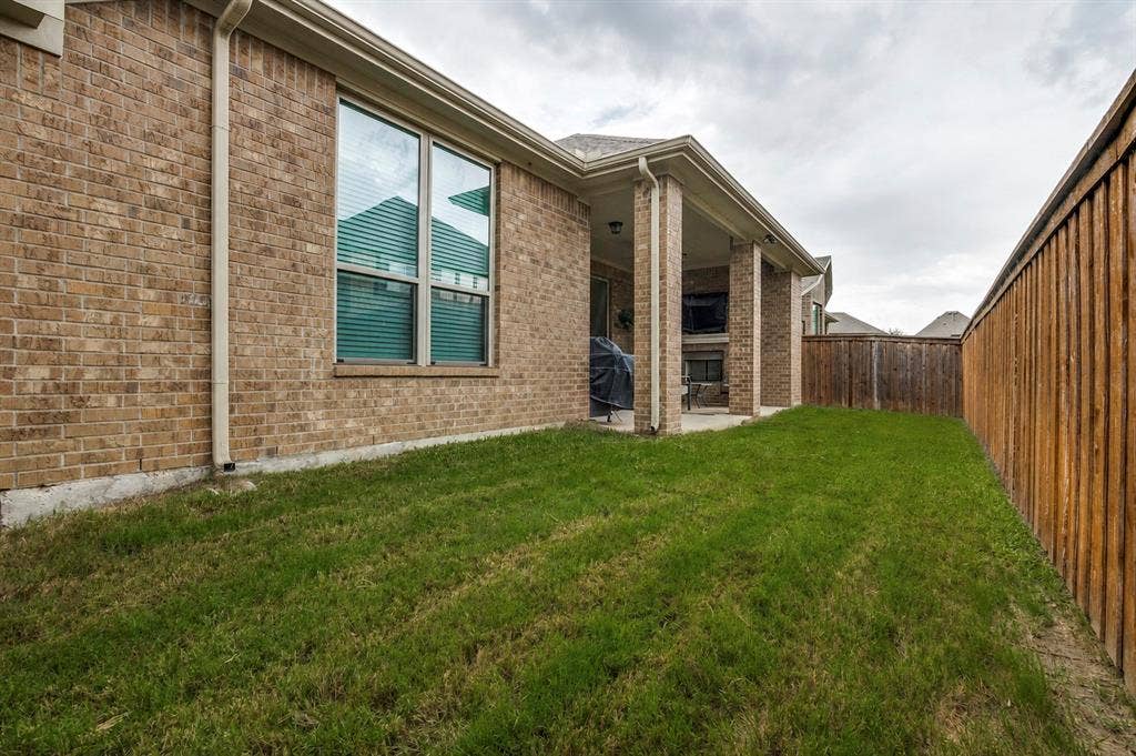 2810 Green Circle Drive, Mansfield, TX 76063 Grassed side yard featuring a privacy fence, brick exterior, single-hung windows, and a covered patio with brick columns