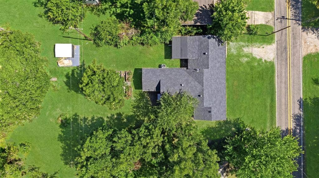 337 N 1st Street, Point, TX 75472 Aerial perspective showcasing a property with a dark shingle roof, surrounded by mature trees and verdant lawns