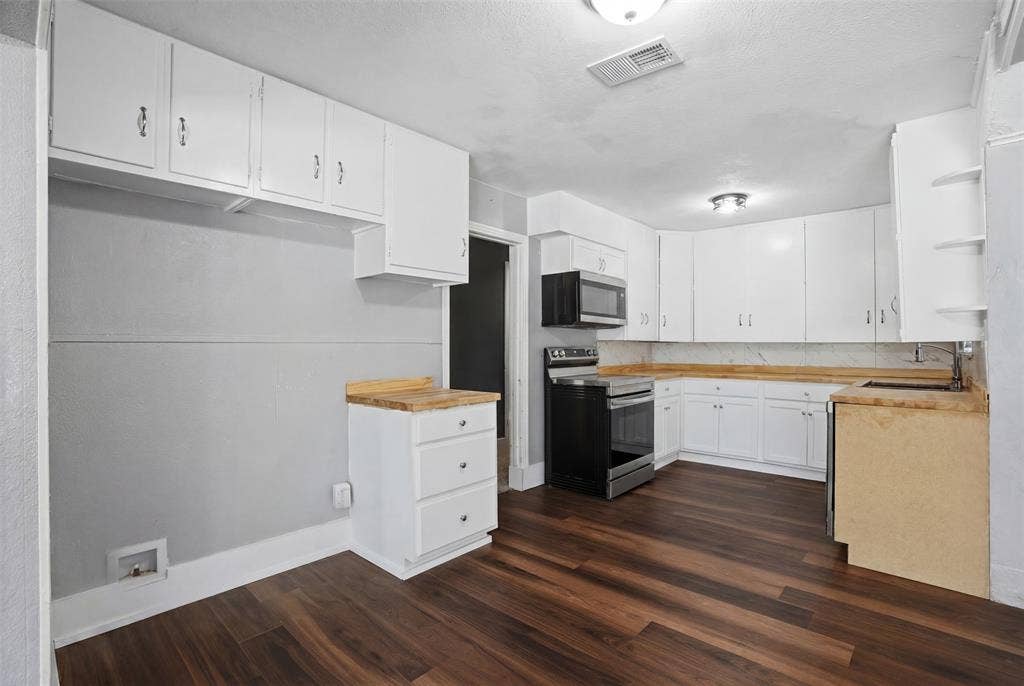 337 N 1st Street, Point, TX 75472 Kitchen featuring dark wood-finish flooring, white cabinetry, a stainless steel microwave, and a stainless steel electric range