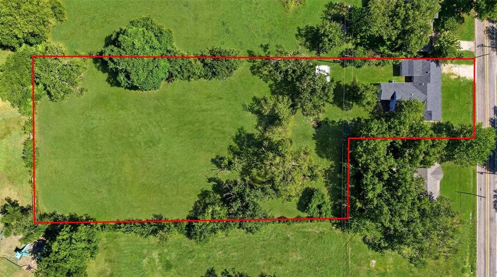 337 N 1st Street, Point, TX 75472 Expansive property showcasing a large grassy lot with mature trees, a single-story residence featuring a dark shingle roof, and direct access to a paved road
