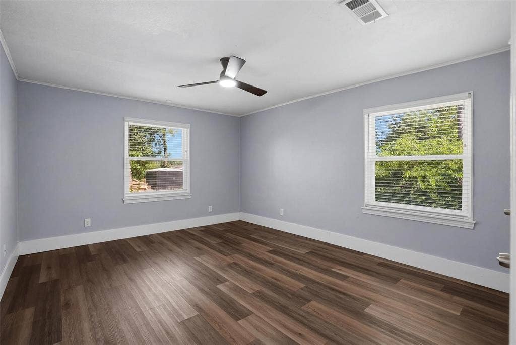 337 N 1st Street, Point, TX 75472 Spacious room featuring wood-finish flooring, light blue walls, two large windows with blinds, a modern ceiling fan, and white crown molding