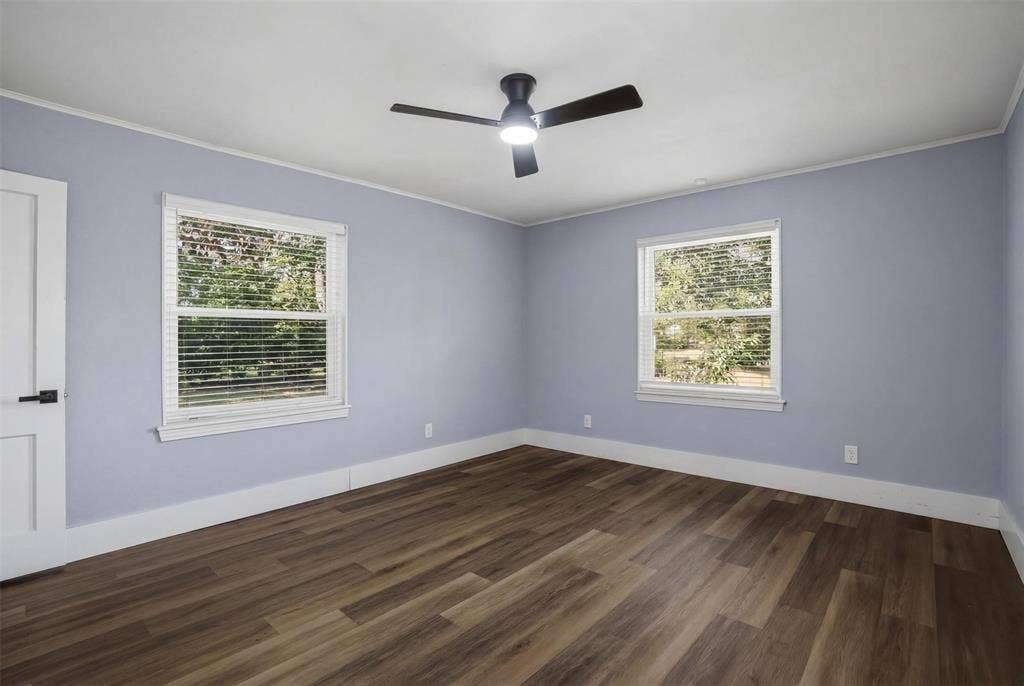 337 N 1st Street, Point, TX 75472 Spacious room featuring wood-finish flooring, two large windows with blinds, a modern ceiling fan with lighting, and a crisp white door with black hardware