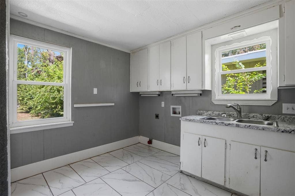 337 N 1st Street, Point, TX 75472 Utility area featuring expansive white-finish cabinetry, a dual-basin sink with a chrome faucet, speckled countertops, and large format tile flooring