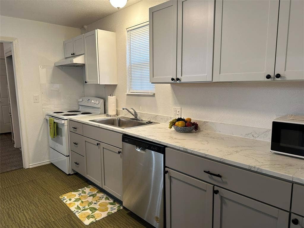 144 Huntoon Trail, Mabank, TX 75156 Kitchen featuring light gray cabinetry with black hardware, white countertops, stainless steel dishwasher, and a white electric range with a coordinating range hood