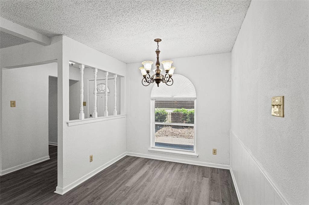 529 Georgetown Drive, Everman, TX 76140 Dining area featuring a decorative chandelier, arched window with horizontal blinds, and wood-finish flooring