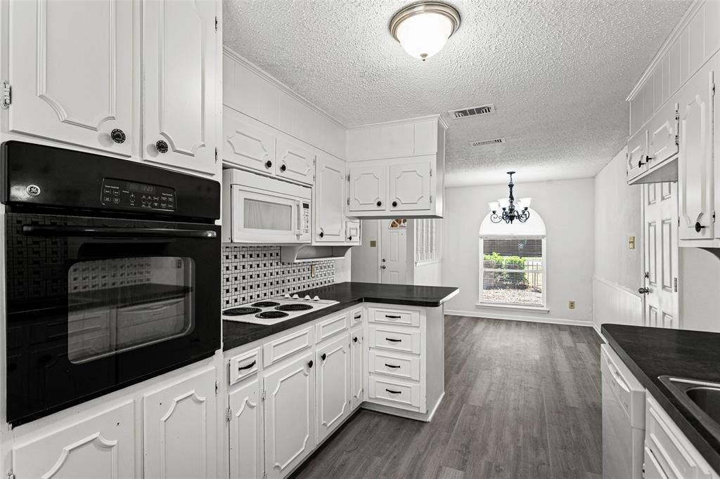 529 Georgetown Drive, Everman, TX 76140 Kitchen featuring white cabinetry, dark countertops, built-in oven, and wood-finish flooring