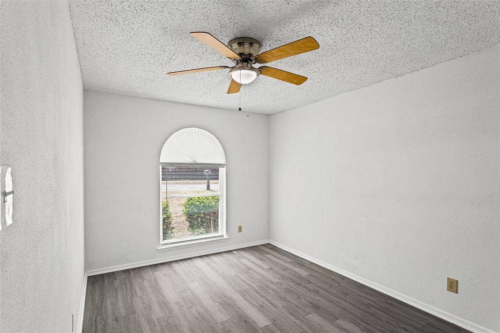 529 Georgetown Drive, Everman, TX 76140 Arch-top window with pleated blind, wood-finish flooring, and ceiling fan with light fixture