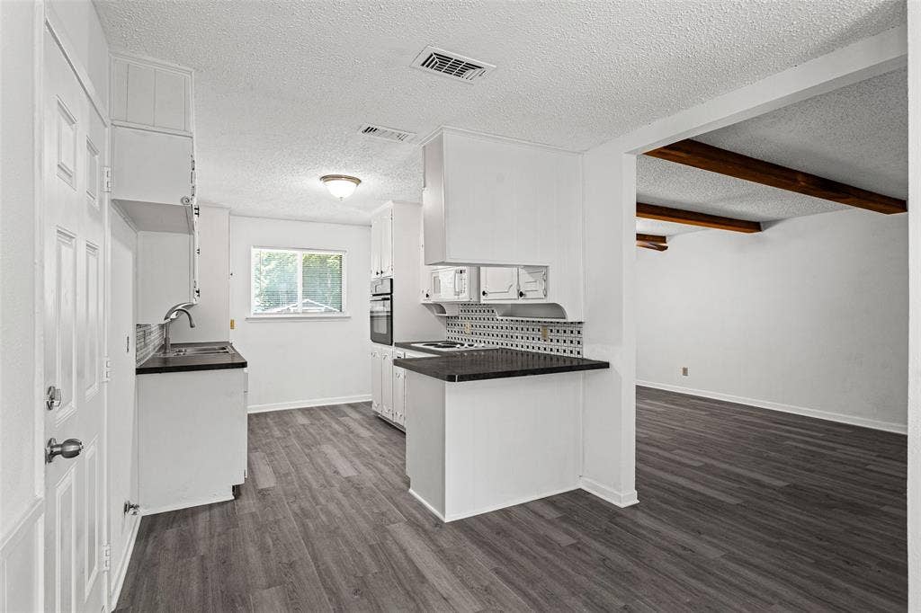 529 Georgetown Drive, Everman, TX 76140 Kitchen featuring shaker-style white cabinetry, dark countertops, a tile backsplash, and wood-finish flooring