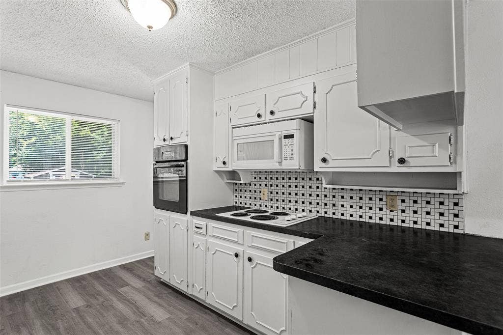 529 Georgetown Drive, Everman, TX 76140 Kitchen featuring white cabinetry, black countertops, a built-in double oven, and wood-finish flooring