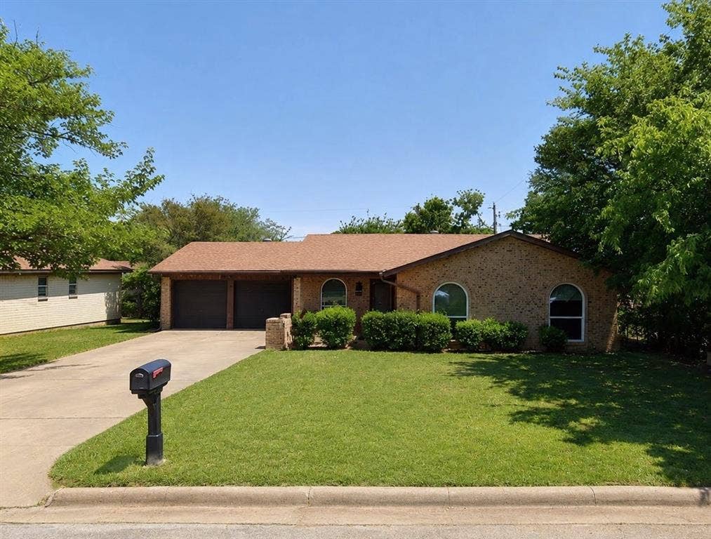 529 Georgetown Drive, Everman, TX 76140 Brick exterior with arched windows and a brown shingle roof