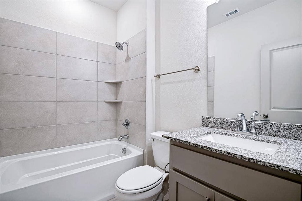 1006 Emil Place, Allen, TX 75013 Bathroom featuring a bathtub with tiled surround and integrated shelving, granite-finish countertop, under-mount sink, and chrome fixtures