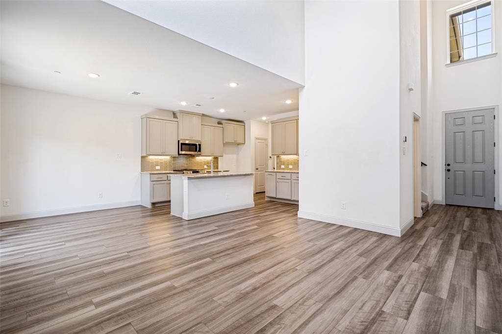 1006 Emil Place, Allen, TX 75013 Open-concept living space featuring wood-finish flooring, a contemporary kitchen, and soaring ceilings