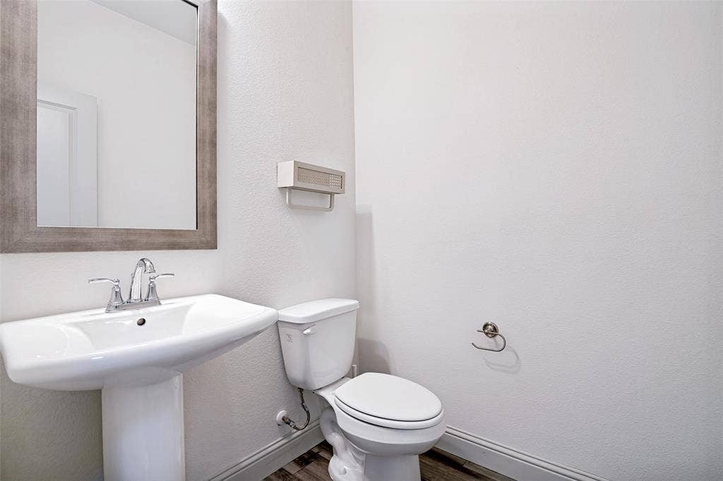 1006 Emil Place, Allen, TX 75013 Pedestal sink with chrome faucet, framed mirror, and wood-finish flooring