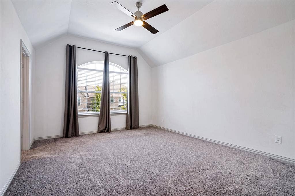 1006 Emil Place, Allen, TX 75013 Spacious room featuring vaulted ceilings, a large arched window with blinds, a ceiling fan, and carpeted flooring