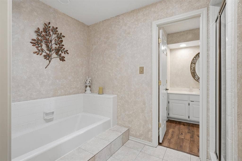 5711 Cortez Drive, Granbury, TX 76049 Bathroom featuring a built-in bathtub with tiled surround, textured wall finish, and tiled flooring