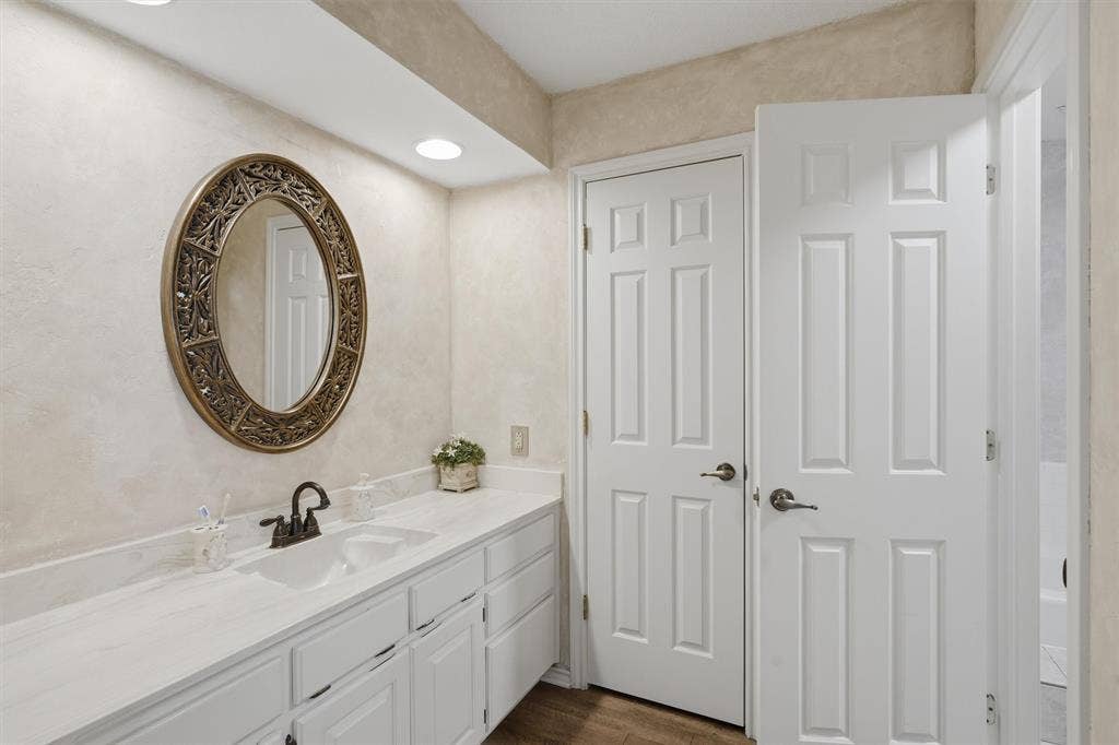 5711 Cortez Drive, Granbury, TX 76049 Double vanity with integrated sinks and white cabinetry, complemented by a large ornate oval mirror