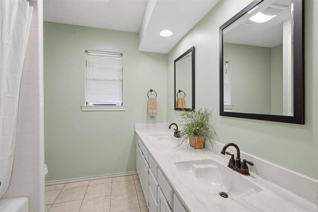 5711 Cortez Drive, Granbury, TX 76049 Double vanity featuring integrated sinks, bronze-finish faucets, and an expansive countertop